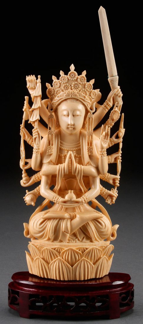 A FINE CHINESE CARVED IVORY FIGURE OF GUAN YIN: A FINE CHINESE CARVED IVORY FIGURE OF GUAN YIN, 20TH CENTURY. Depicting the 18 armed Goddess of Mercy seated on a double lotus throne, her hands grasping various Buddhist accoutrements. Fully carved i