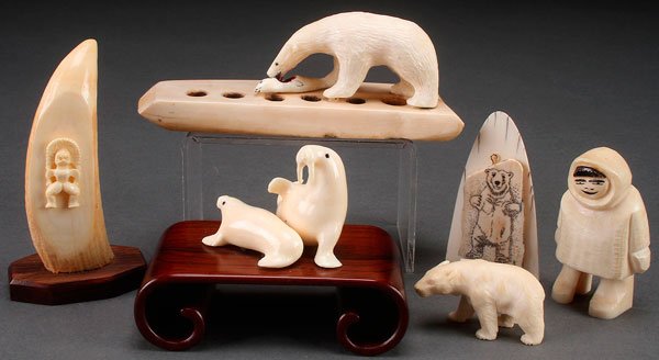 A GROUP OF FIVE ESKIMO AND ALEUTIAN CARVED IVORY: A GROUP OF FIVE ESKIMO AND ALEUTIAN CARVED IVORY FIGURES, 20TH CENTURY. Comprising two walrus on rosewood stand, a carved whale's tooth, a carved polar bear plaque, a carved polar bear and salmon grou