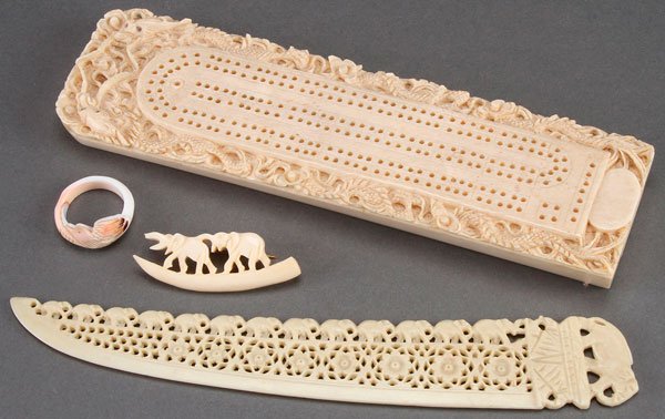 A CHINESE EXPORT CARVED IVORY CRIBBAGE BOARD: A CHINESE EXPORT CARVED IVORY CRIBBAGE BOARD, FIRST HALF 20TH CENTURY. With Hong Kong "Hang On Ivory Store Products" label carved with a dragon border, an ivory elephant pin, a carved shell ring and a