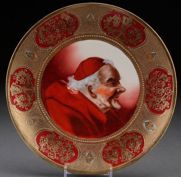 HAND PAINTED NIPPON PORTRAIT PLATE, CIRCA 1915.: HAND PAINTED NIPPON PORTRAIT PLATE, CIRCA 1915. With a scene of a cardinal surrounded by a wide border of six enameled gilt scrolled cartouches. Signed with green “maple leaf” mark. Diameter 9.5 i