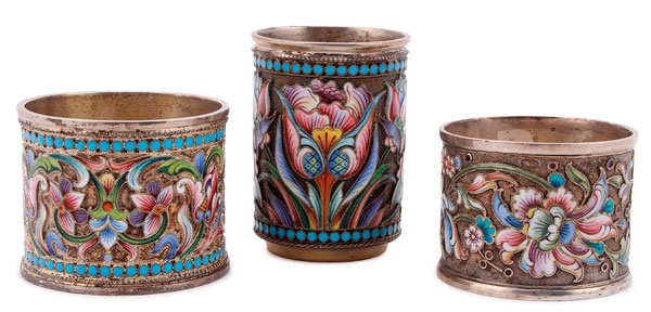 THREE RUSSIAN SILVER-GILT AND ENAMELED ITEMS: A GROUP OF THREE RUSSIAN SILVER-GILT AND SHADED ENAMEL ITEMS, MOSCOW, 1896-1917. Comprising two napkin rings with overall shaded enameled florals on a stippled gilt ground and one incorporating a parr