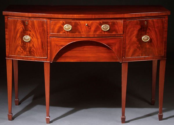 ENGLISH SHERATON MAHOGANY BOW FRONT SIDEBOARD C1800: AN ENGLISH SHERATON MAHOGANY BOW FRONT SIDEBOARD, CIRCA 1800. With break front lower drawer, raised on square tapering legs, and cock beaded drawer surrounds. Height 35.75 inches (90.6 cm), width 52 i