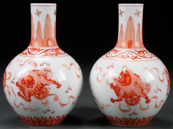 PAIR CHINESE RED OXIDE DECORATED "FOO LION" VASES: A PAIR OF CHINESE RED OXIDE DECORATED "FOO LION" PORCELAIN VASES. Of squat bulbous form, each with three Foo lions and Buddhist symbols accented in gilt. Bases with Guangxu marks. Height 7 inches (17.