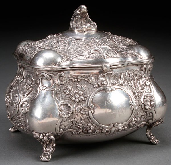 A GERMAN SILVER LIDDED DRESSER BOX, LATE 19TH CENTURY: A GERMAN SILVER LIDDED DRESSER BOX, LATE 19TH CENTURY. Of Rococo style with repoussed florals, strapwork and scalloped cartouches on a stippled ground. The base stamped with a crescent, crown, 800 and