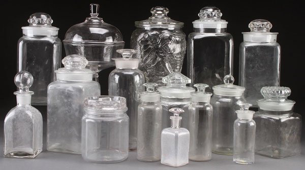 16 APOTHECARY AND CANDY JARS: APOTHECARY AND CANDY JARS, EARLY 20TH CENTURY. A group of 16 various pressed glass drug store apothecary and candy jars, all with lids and stoppers. Height ranging 6.25 inches (15.8 cm) to 12.5 inches