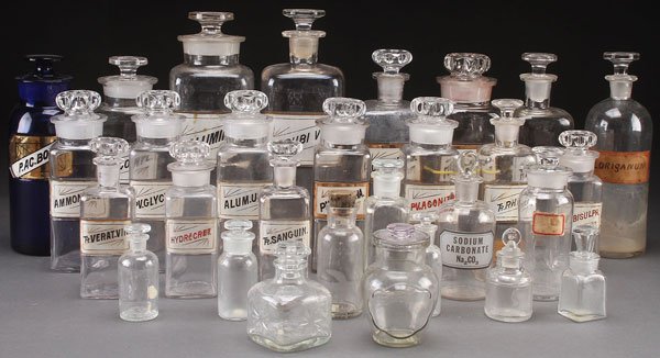 31 APOTHECARY DRUG STORE JARS: APOTHECARY DRUG STORE JARS, EARLY 20TH CENTURY. A group of 31 drug store apothecary jars with reverse painted labels and glass stoppers in various sizes and condition. Height ranging 4 inches (10.2 cm