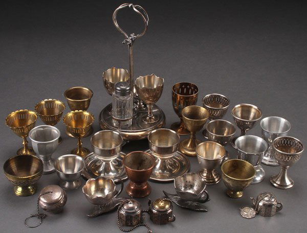 A SILVER PLATE EGG CUP AND TEA BALL COLLECTION: A SILVER PLATE EGG CUP AND TEA BALL COLLECTION, 19TH CENTURY AND LATER. Comprising a Victorian two egg stand with cups, salt dip and pepper shaker, two Victorian leaf base egg cups, plus a variety of