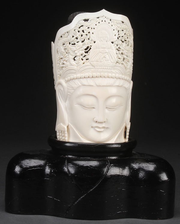 A CHINESE EXPORT CARVED IVORY BUDDHIST BUST,: A CHINESE EXPORT CARVED IVORY BUDDHIST BUST, PROBABLY LATE QING DYNASTY. With reticulated crown depicting a seated Buddha and dragon forms, raised on a carved hardwood should form base. Ivory height 6
