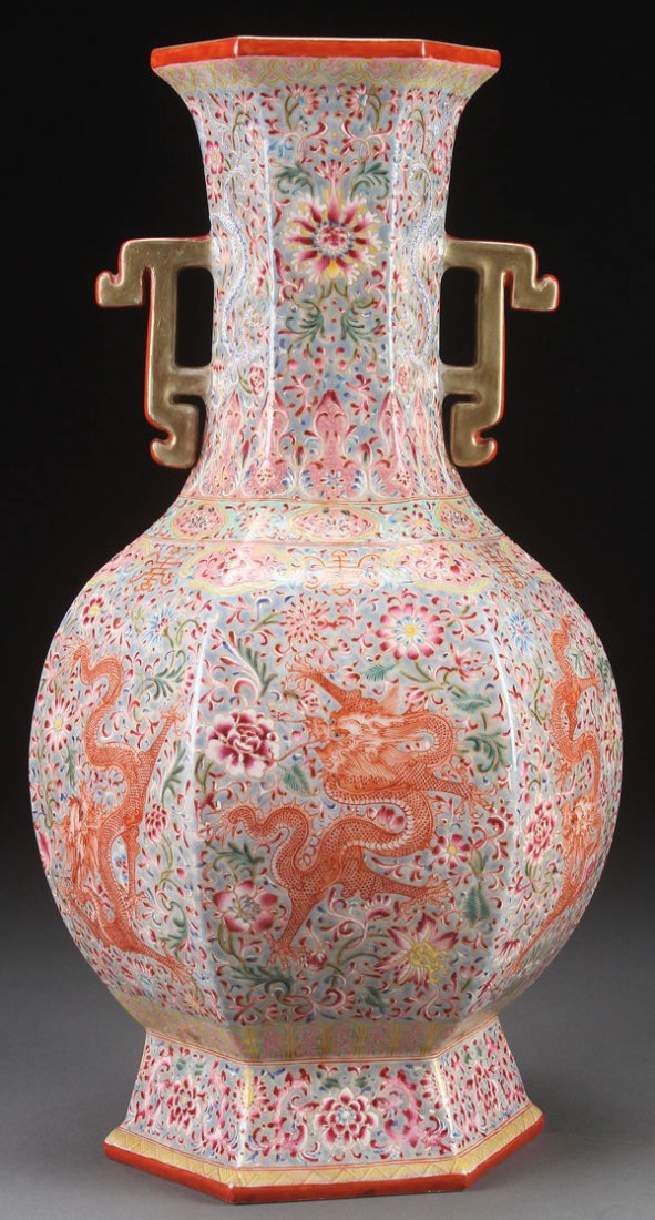 A CHINESE FAMILLE ROSE PORCELAIN "DRAGONS" VASE.: A CHINESE FAMILLE ROSE PORCELAIN "DRAGONS" VASE. Of hexagonal baluster form with stylized flange handles, each panel decorated with an iron red dragon on a dense floral ground. Base with Qianlong Nian