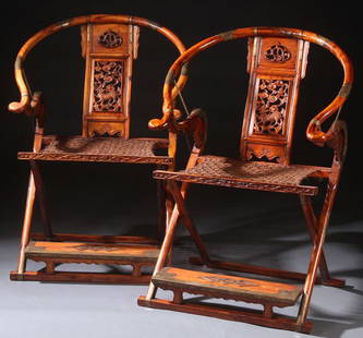 PAIR OF CHINESE HORSESHOE BACK FOLDING HUNTERS CHAIRS: A LARGE PAIR OF CHINESE HORSESHOE BACK FOLDING HUNTERS CHAIRS, 20TH CENTURY. With reticulated carved back panels, mounted brass attachments, and woven seats, in amber colored wood with highly figured