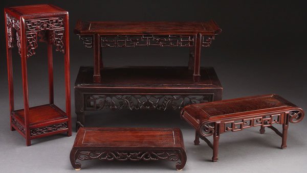 A GROUP OF FIVE CHINESE CARVED HARDWOOD STANDS: A GROUP OF FIVE CHINESE CARVED HARDWOOD STANDS, 20TH CENTURY. Comprising four miniature altar tables and a tall rectangular stand, each with reticulated carved panels in mahogany and rosewood. One wit