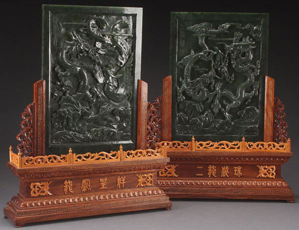 2 CHINESE CARVED SPINACH JADE TABLE SCREENS: A PAIR OF CHINESE CARVED SPINACH JADE TABLE SCREENS, 20TH CENTURY. Each contained in carved hardwood stands, the plaques carved in deep relief with battling dragons and phoenix. 8 inches x 11 inches (