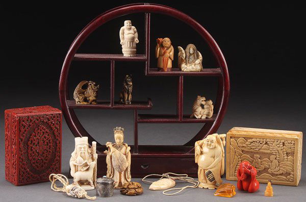 A GROUP OF ORIENTAL DECORATIVE ARTS: A GROUP OF ORIENTAL DECORATIVE ARTS, 19TH/20TH CENTURY. 18 pieces, comprising various carved netsukes and other figures, red and white cinnabar lidded boxes, and a mahogany netsuke display. Largest he