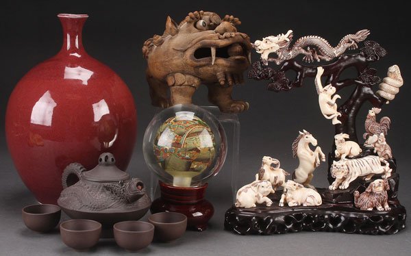 A GROUP OF ORIENTAL DECORATIVE ARTS, 20TH CENTURY: A GROUP OF ORIENTAL DECORATIVE ARTS, 20TH CENTURY. Comprising a contemporary red glazed bottle vase, a dragon ware pottery tea set, a large hand modeled pottery beast, a reverse painted glass sphere o