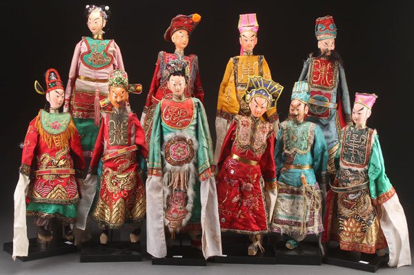 A GROUP OF 10 CHINESE THEATRICAL COSTUME PUPPETS,: A GROUP OF 10 CHINESE THEATRICAL COSTUME PUPPETS, 20TH CENTURY. Jointed wood with polychrome features, each dressed in elaborately embroidered court robes with silver and gilt threading. Largest lengt