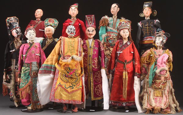 A GROUP OF 11 CHINESE THEATRICAL COSTUME PUPPETS,: A GROUP OF 11 CHINESE THEATRICAL COSTUME PUPPETS, 20TH CENTURY. Jointed wood with polychrome features, each dressed in elaborately embroidered court robes with silver and gilt threading. Largest lengt