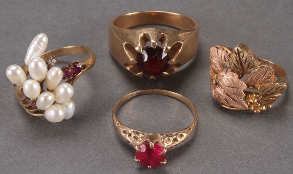 A GROUP OF FOUR GOLD RINGS: A GROUP OF FOUR GOLD RINGS, 20TH CENTURY. Comprising a mans 10k with garnet; a womans river pearl, ruby and diamond ring, stamped 14k; a womans black hills gold leaf decorated ring; and an unmarked go