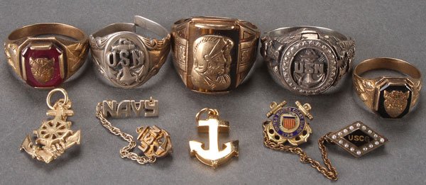 NINE MENS MILITARY AND CLASS RINGS: AN NINE PIECE MENS MILITARY AND CLASS RING JEWELRY GROUP, 20TH CENTURY. Comprising two sterling “USN” rings, a sterling “USN” lapel pin, a 10k tiger eye and gold cameo ring, a 10k Forest City 