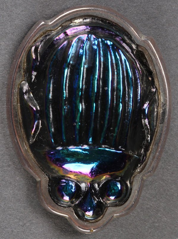 A TIFFANY & CO. IRIDIZED GLASS &STERLING SCARAB PIN: A TIFFANY & CO. IRIDIZED GLASS AND STERLING SCARAB PIN, 20TH CENTURY. The molded and iridized scarab beetle form body set in a conforming sterling bezel, stamped on verso “Tiffany & Co.” and conta