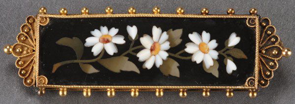 LADIES VICTORIAN 18K GOLD PIETRA DURA FLORAL PIN: A LADIES VICTORIAN 18K GOLD PIETRA DURA FLORAL PIN. Comprising a rectangular panel inlaid with white floral blossoms and leaves on a black ground, set in a beaded and coiled gold wire frame. Length 2.