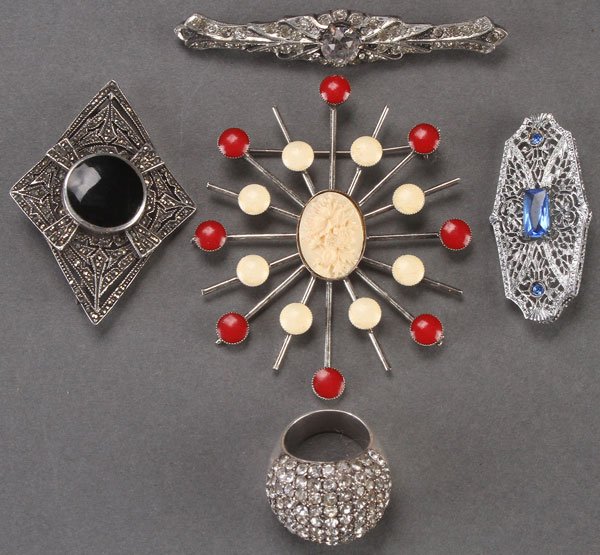 A FIVE PIECE VINTAGE JEWELRY GROUP: A FIVE PIECE DECORATIVE JEWELRY GROUP. Comprising an Art Deco sterling, marcasite and jet pin; a rhinestone bar pin; an interesting starburst pin; a filigree deco pin with blue stones; and a sterling 