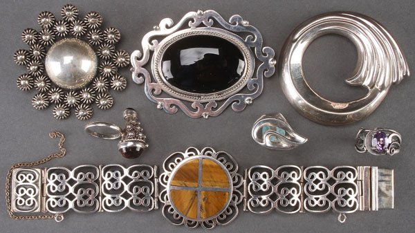 SEVEN PIECE MOSTLY MEXICAN SILVER JEWELERY: A SEVEN PIECE GROUP OF MOSTLY MEXICAN SILVER JEWELRY, LATE 20TH CENTURY. Comprising a heavy reticulated bracelet with inlaid tiger-eye, a rosette for pin, a stylized pin, a scrolled and black onyx pin