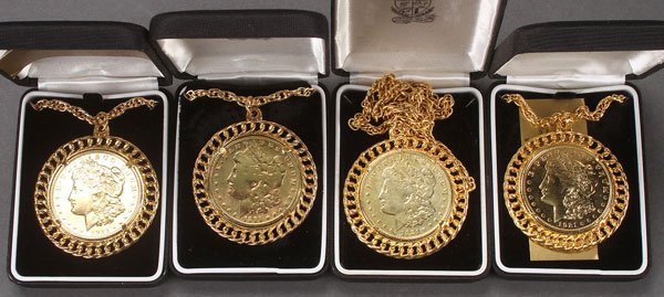 A GROUP OF FOUR GOLD PLATED MORGAN SILVER DOLLARS: A GROUP OF FOUR GOLD PLATED MORGAN SILVER DOLLARS. Set in gold plated frames with chains. Three dated 1921 and one dated 1901.