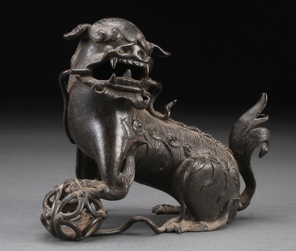 A CHINESE BRONZE BUDDHIST LION: A CHINESE BRONZE BUDDHIST LION, LATE MING/QING DYNASTY. Depicting a well cast figure with left paw on reticulated ball, nice dark patina. Length 6.5 inches (16.5 cm).