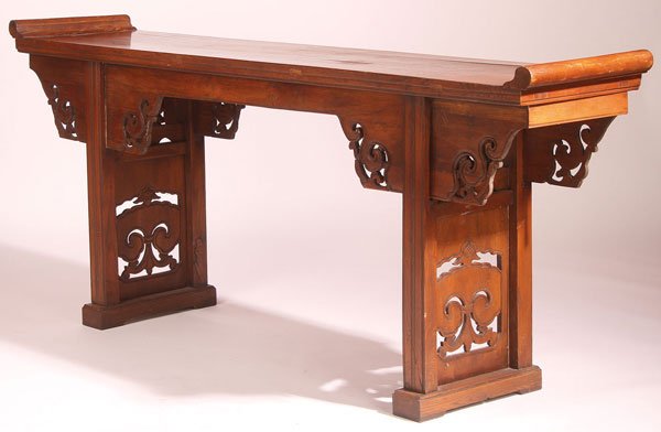 A CHINESE CARVED ELM WOOD ALTAR TABLE, 19TH C: A CHINESE CARVED ELM WOOD ALTAR TABLE, 19TH CENTURY. With upturned scrolled terminals, raised on four fluted legs, joined with pierced carved panels representing a fungus form, below scroll and pierce