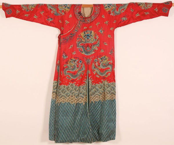 A CHINESE EMBROIDERED SILK WINTER COURT ROBE: A CHINESE EMBROIDERED SILK WOMAN'S INFORMAL WINTER COURT ROBE, 20TH CENTURY. Finely stitched with dragons, gilt threads, and Buddhist symbols on a red ground, above a wavy blue border. Width 70 inches