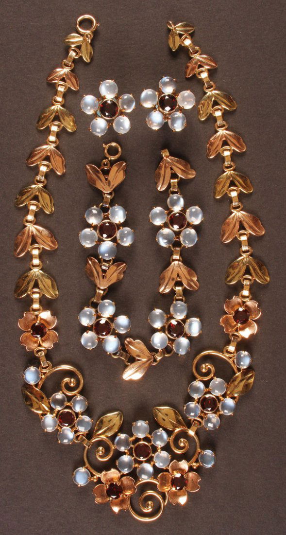 TIFFANY & CO. 14K GOLD, MOONSTONE & GARNET SET: A VERY FINE TIFFANY & CO. 14K GOLD, MOONSTONE AND GARNET DEMI-PARURE, CIRCA 1940. Comprising a two-tone gold necklace, bracelet and earrings. Of floral and foliate design, the flower heads with center