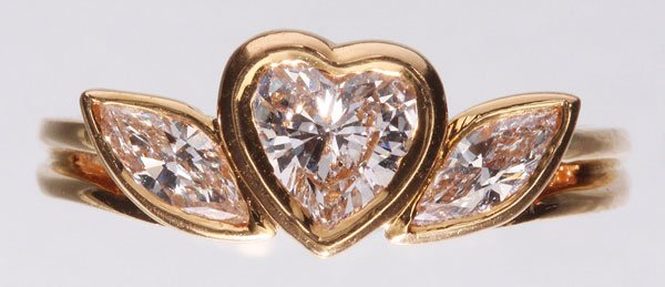 OSCAR HEYMAN & BROS. 18K GOLD AND DIAMOND RING: A GOOD OSCAR HEYMAN & BROS. 18K GOLD AND DIAMOND RING, LATE 20TH CENTURY. The heart shaped bezel set diamond flanked by two bezel set marquis cut diamonds of very fine color and clarity. Stamped 18K a