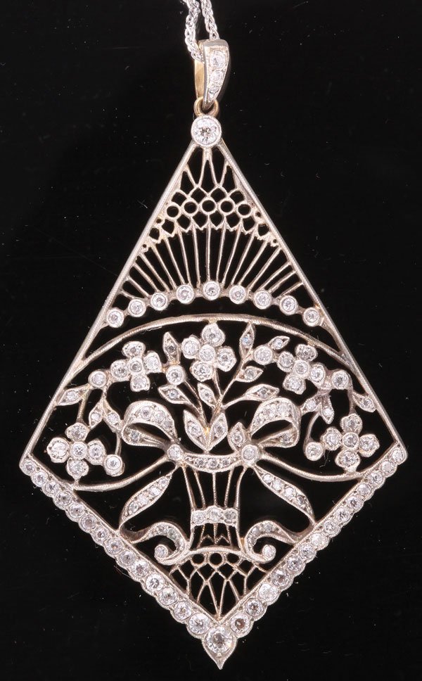 AN EDWARDIAN DIAMOND AND GOLD PENDANT.: AN EDWARDIAN DIAMOND AND GOLD PENDANT. Mounted as an openwork navette shaped plaque, set with European cut diamond floral motifs, further accented by diamond collets, mounted in silver and gold, suspe