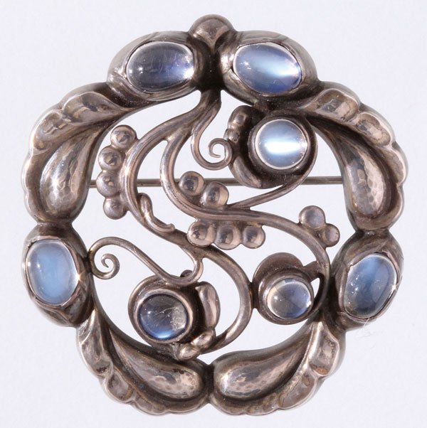 GEORG JENSEN LABRADORITE AND STERLING BROOCH: A VERY FINE GEORG JENSEN LABRADORITE AND STERLING SILVER FOLIATE BROOCH, AFTER 1945. Of circular scrolled foliate form with carved leaves and berries, containing seven blue rainbow cabochon labradorit