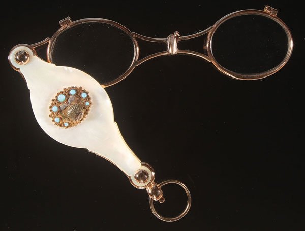 A VICTORIAN GOLD AND MOTHER OF PEARL LORGNETTE.: A VICTORIAN GOLD AND MOTHER OF PEARL LORGNETTE. The folding eyeglass in gold frame held within conforming mother of pearl covers, the obverse with applied tri-tone gilt shell and carved foliate medall