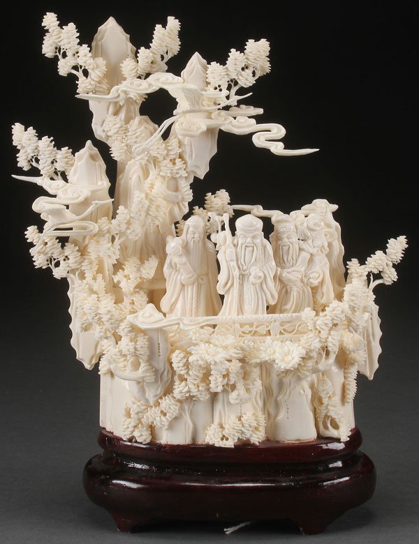 CHINESE CARVED BONE SCENIC GROUPING OF IMMORTALS: A CHINESE CARVED BONE SCENIC GROUPING OF IMMORTALS, EARLY 20TH CENTURY. Depicting three immortals and an attendant within a mountain setting surrounded by pine trees, clouds, and flying cranes, rais