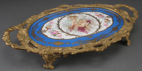 A SEVRÉS STYLE PORCELAIN AND GILT BRONZE DRESSER: A SEVRÉS STYLE PORCELAIN AND GILT BRONZE DRESSER TRAY, CIRCA 1900. With putti and florals, spurious Sevrés backstamp, and inscribed "France." Length 15 inches (38 cm).