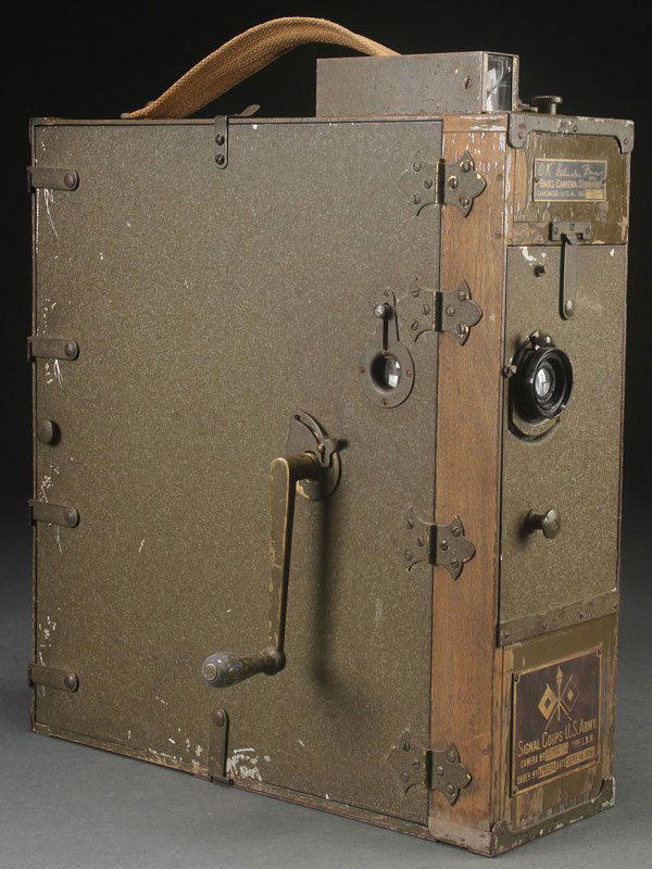 A BASS 35mm U.S. ARMY SIGNAL CORP MOTION PICTURE: A BASS 35mm U.S. ARMY SIGNAL CORP MOTION PICTURE CAMERA, EARLY 20TH CENTURY. The wood and metal case in olive drab finish web strap handle and removable sight finder with Bass camera company label an