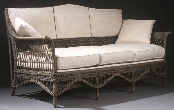 A THREE PIECE CALTEX WOVEN WICKER PORCH SUITE: A THREE PIECE CALTEX WOVEN WICKER PORCH SUITE, EARLY 20TH CENTURY. Comprising a three cushion sofa, rocker, and arm chair, the sofa with later upholstery. Largest length 75.6 inches (192 cm), height 3