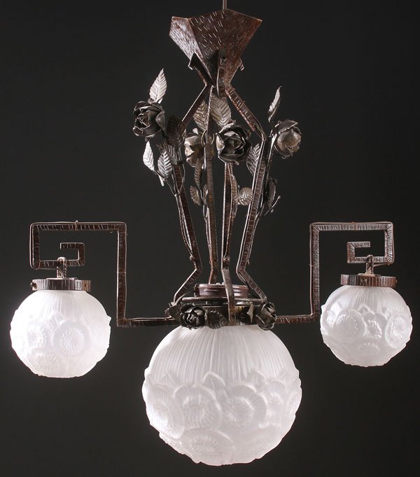 A FRENCH ART DECO WROUGHT IRON FROSTED AND MOLDED: A FRENCH ART DECO WROUGHT IRON FROSTED AND MOLDED GLASS THREE LIGHT CHANDELIER, CIRCA 1920S. The wrought iron fixture with applied rose blossoms and leaves suspending a central stylized floral cirpher