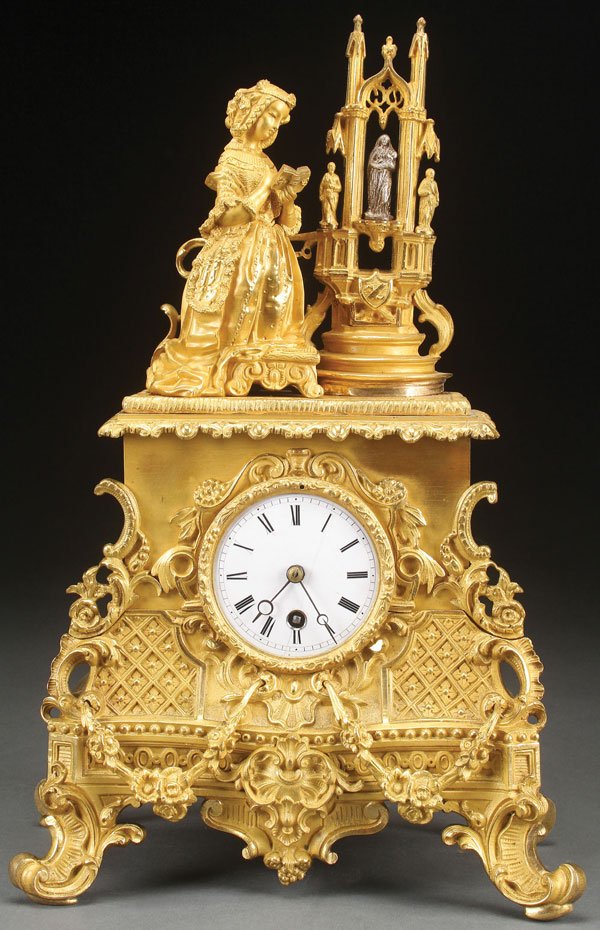 A LOUIS THE XV STYLE GILT BRONZE MANTLE CLOCK: A LOUIS THE XV STYLE GILT BRONZE MANTLE CLOCK, LATE 19TH CENTURY. Surmounted with a figure of a young girl in period dress reading a prayer book beside a Gothic shrine. Height 16.25 inches (41.2 cm).