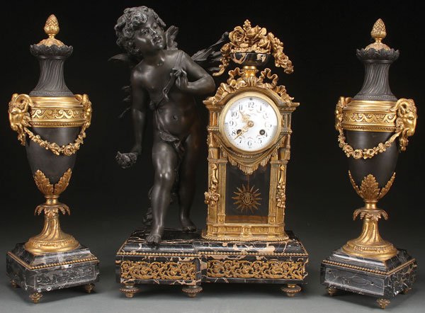 A FRENCH GILT SPELTER AND MARBLE FIGURAL CLOCK: A FRENCH GILT SPELTER AND BLACK MARBLE FIGURAL CLOCK GARNITURE, EARLY 20TH CENTURY. The crystal regulator in an ornate gilt spelter case with floral decorated porcelain dial, and surmounted with an ur