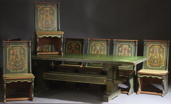 A GREAT HALL TRESSEL DINING TABLE AND SIDE CHAIR: A GREAT HALL TRESSEL DINING TABLE AND SIDE CHAIRS IN THE SCANDINAVIAN TASTE, EARLY 20TH CENTURY. The thickly slabbed table supported by a tressel base joined with pegged tenon stretchers decorated in 