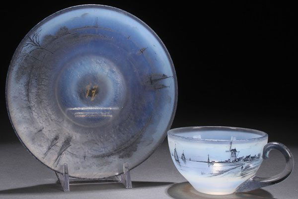 A FRENCH DAUM NANCY ENAMELED ART GLASS CUP & SAUCER: A FRENCH DAUAM NANCY SCENIC CUP AND SAUCER, EARLY 20TH CENTURY. In semi-translucent opal glass with charcoal enameled harbor scenes. The pontils inscribed "Daum Nancy with Croix De Lorraine." Diamete