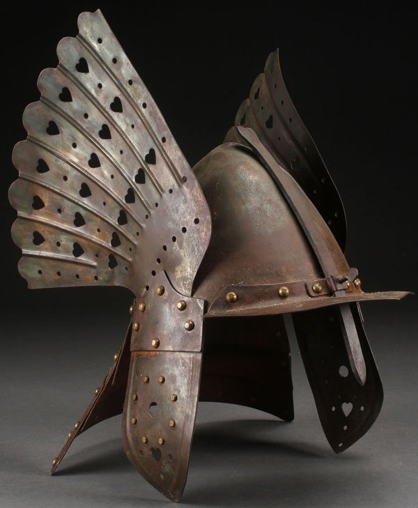 AN INTERESTING METAL HELMET, 20TH CENTURY: AN INTERESTING METAL HELMET, 20TH CENTURY, PROBABLY GERMAN. With lobster tail neck guard, elaborate side wing guards pierced with hearts and with overhanging bill and adjustable face guard. Apparently