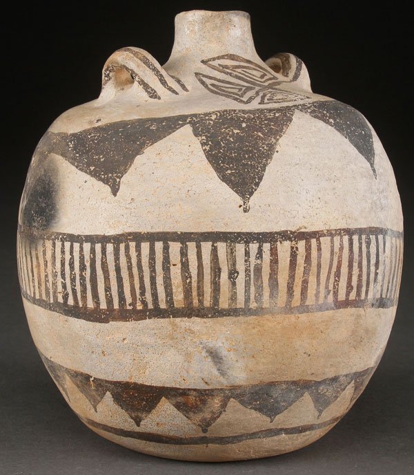 RESERVE BLACK ON WHITE POTTERY CANTEEN: A FINE PRE HISTORIC RESERVE BLACK ON WHITE POTTERY CANTEEN, MOGOLLON, A.D. 1100-1200. With two applied handles on shoulder flanking a slender neck above geometric designs. Some restorations. Height 7 