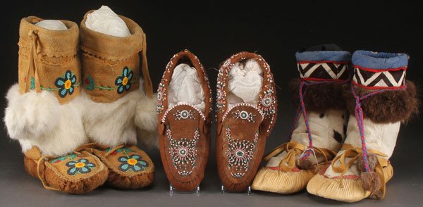 A NATIVE AMERICAN HIDE FOOTWEAR GROUP, 20TH C.: A NATIVE AMERICAN HIDE FOOTWEAR GROUP, 20TH CENTURY. Comprising a pair of seal skin mukluks, a pair of Cree partially beaded and fur trimmed high top moccasins and a pair of partially beaded moccasins