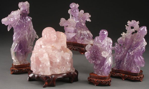 A GROUP OF FIVE CHINESE CARVED AMETHYST: A GROUP OF FIVE CHINESE CARVED AMETHYST AND ROSE QUARTZ FIGURAL GROUPS, LAST HALF OF THE 20TH CENTURY. Of various form including Kwan Yin, Buddha, and immortals. All raised on hardwood stands. The lar