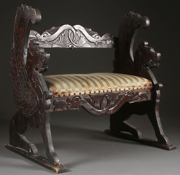 A NORWEGIAN FIGURAL CARVED OAK HALL SEAT: A NORWEGIAN FIGURAL CARVED OAK HALL SEAT IN THE GOTHIC STYLE, LATE 19TH CENTURY. With each end panel carved with figural winged griffins and joined by a stretched carved with foliate relief. Height 29