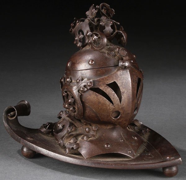 GOTHIC STYLE KNIGHTS HELMET INKWELL 19TH C.: AN EARLY GOTHIC REVIVAL PATINATED STEEL INKWELL, PROBABLY GERMAN, 19TH CENTURY. Modeled as a Medieval helmet with pierced visor with applied cut and chased steel scrolled acanthus ornaments. Raise